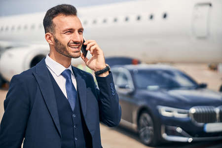 Businessman talking on the phone near an airplane