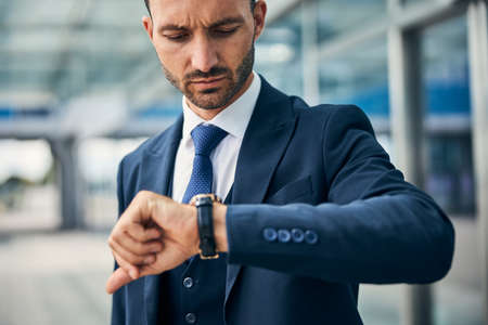 Serious man checking the time on his watch