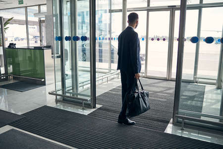 Young man leaving the airport with his luggageの写真素材