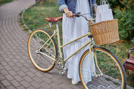 Beautiful woman with white shopping bags in basket on vintage bicycleの写真素材