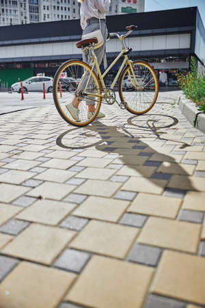 Yellow bike and beautiful woman standing on the asphaltの写真素材