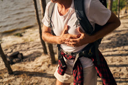 Man complaining on pain in chest while hikingの写真素材