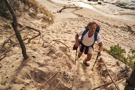 Athletic male going nordic walking near sea shoreの写真素材