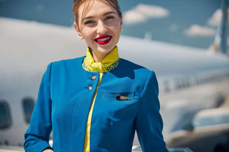Beautiful young stewardess standing outdoors at airportの写真素材