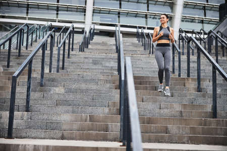 Smiling sporty woman going running in city centreの写真素材