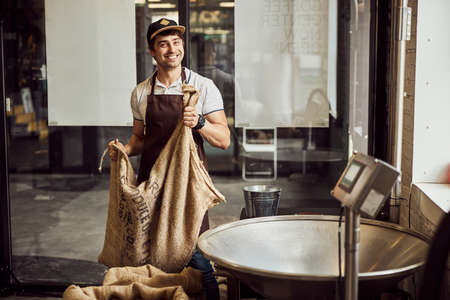 Cheerful young man holding bag with coffee beans