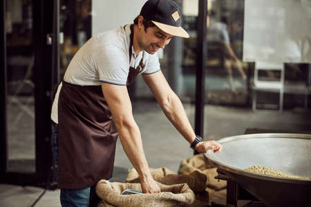 Cheerful male worker standing by metal hopperの写真素材