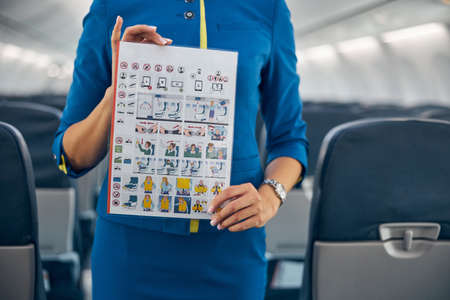 Professional flight attendant demonstrating flight safety information on an airplaneの写真素材