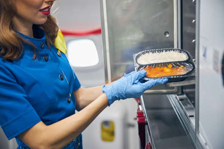 Stewardess serving food to the passengers at the kitchen of commercial airplaneの写真素材
