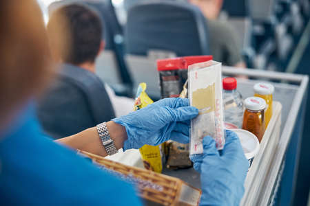 Flight attendant in protective gloves providing service of international airlinesの写真素材