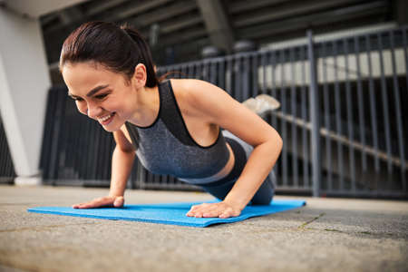 Merry young woman enjoying workout on mat