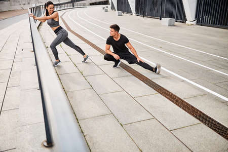 Jolly young couple training together in open air