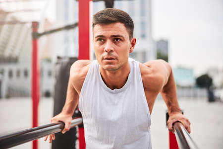 Muscular man training with self weight outdoors