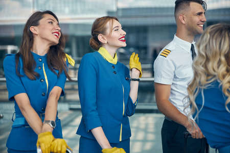 Cheerful stewardesses and pilots standing on the streetの写真素材