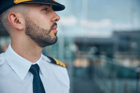 Handsome male pilot in captain hat standing on the street