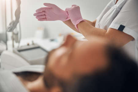 Cosmetologist putting on sterile gloves before cosmetic procedureの写真素材