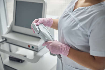 Young female beautician holding IPL laser device