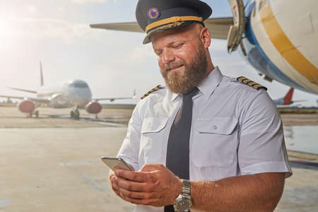 Positive pilot using his modern gadget outdoorsの写真素材