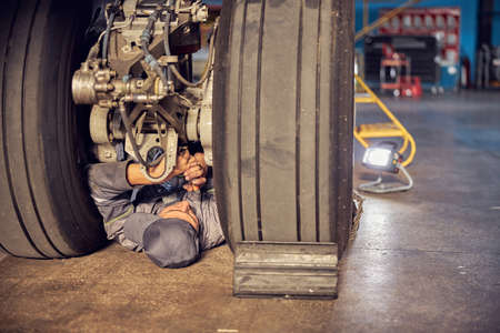 Man is working on airplane under wheelsの写真素材
