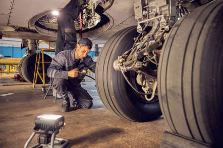 Landing gear airplane in hangar chassis rubber with aviation worker in uniformの写真素材