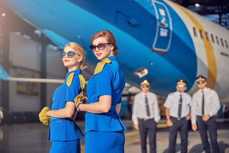 Stylish females stewardesses in sunglasses felling happy while working in the airportの写真素材