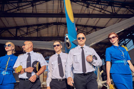 Confident males with beautiful females in business uniform spending time in the parking garage of airplaneの写真素材