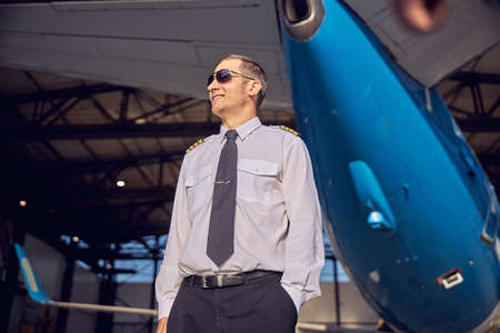 Smiling handsome man standing near the aviation hangar