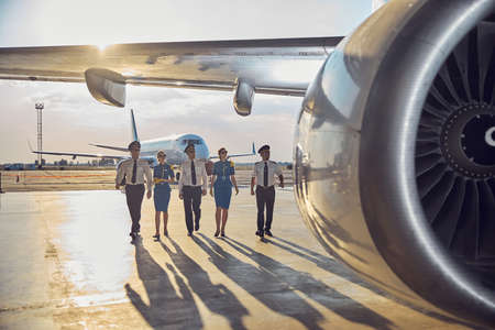 Three men pilots with two stewardesses isolated on big airplaneの写真素材