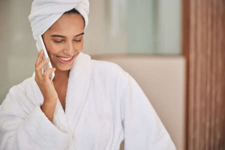 Beautiful young woman talking on mobile phone after shower