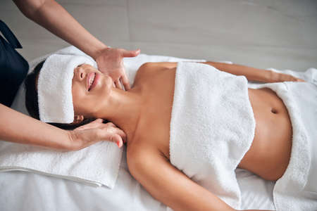 Masseur hands massaging female neck in spa salonの写真素材