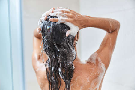 Young woman washing her hair in showerの写真素材