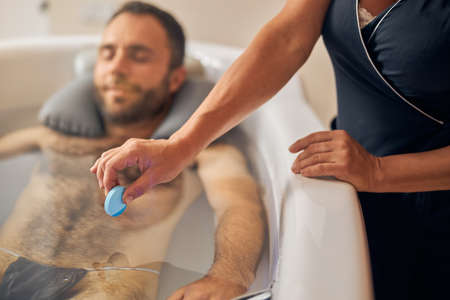 Bearded young man taking revitalizing bath in spa salon