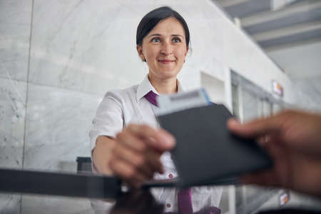 Smiling woman helping passenger with checking in at airportの写真素材