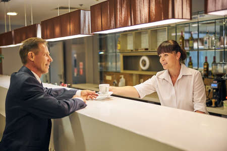 Smiling mature businessman drinking coffee at barの写真素材