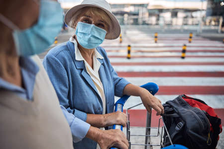Elderly lady and her spouse standing outdoorsの写真素材