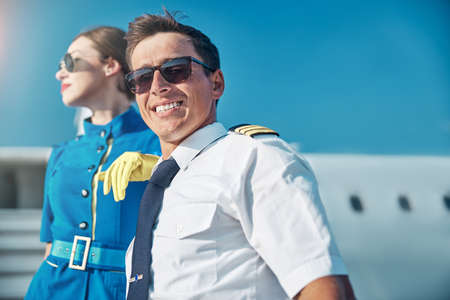 Happy young pilot resting after flight with colleague outdoorsの写真素材