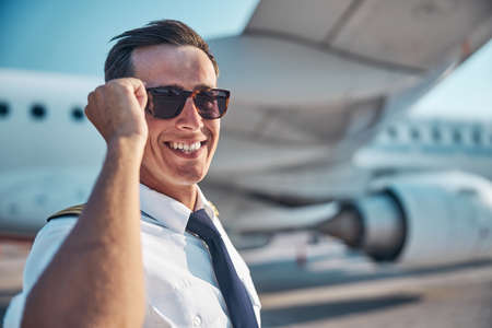 Joyful handsome pilot relaxing outdoors near jetの写真素材
