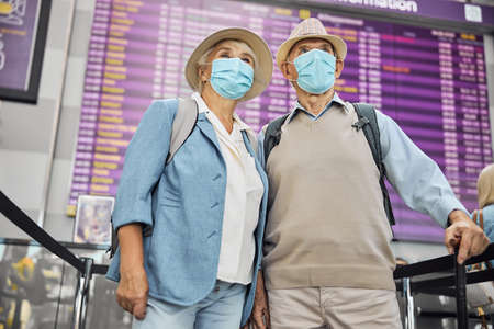 Senior woman and her husband standing at the airportの写真素材