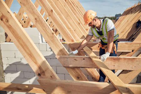 Professional builder in protective equipment building a roofの写真素材