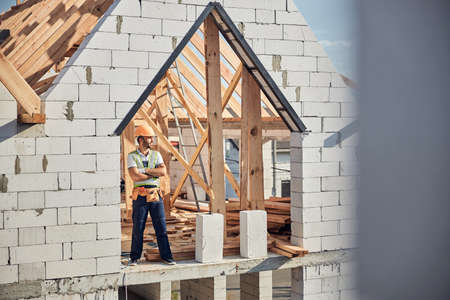 Self-assured builder in a hardhat posing at his workplaceの写真素材