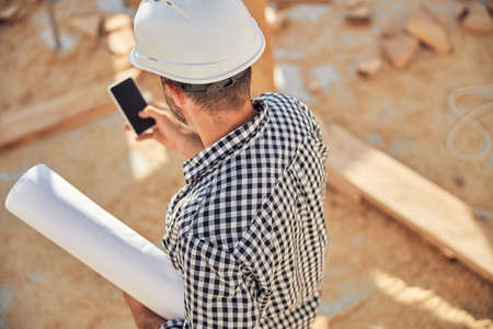 Busy architect with a roll of blueprints and a phoneの写真素材