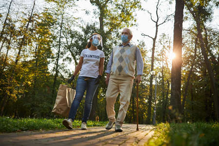 Woman volunteer talking with elderly man in the city park