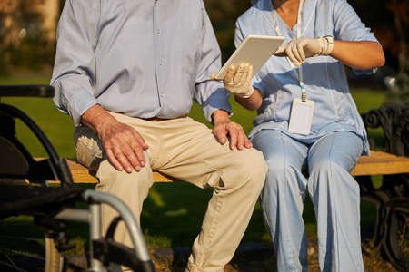Female holding white tablet in hands while sitting near the man