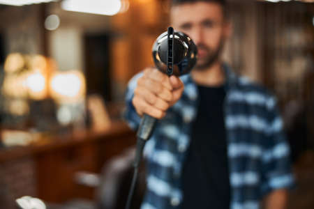 Male barber holding hair dryer like gunの写真素材