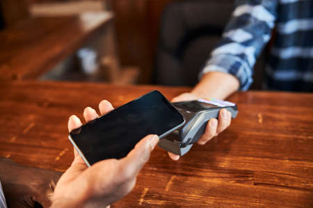Male customer using smartphone for contactless paymentの写真素材