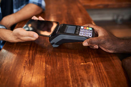 Male customer using mobile phone for contactless payment