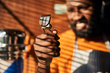 Afro American young man holding portable hair trimmer