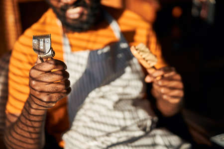 Afro American man holding vintage hair trimmer and brush