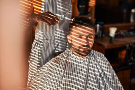 Bearded young man getting haircut in barbershop