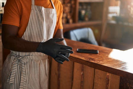 Male barber putting black sterile gloves on hands